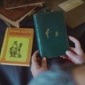 First edition Winne-the-Pooh being held with another book in background. Credit, UQ